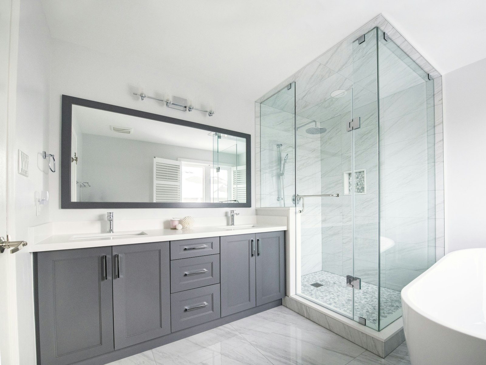 Bright bathroom with a grey double vanity, large mirror and glass walk-in shower