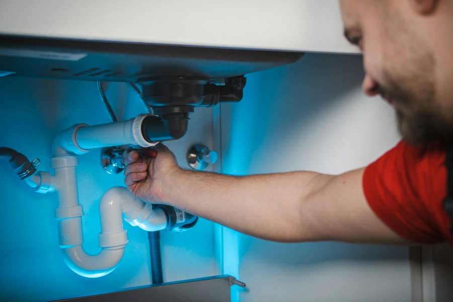Plumber tightening the drain pipes under a sink